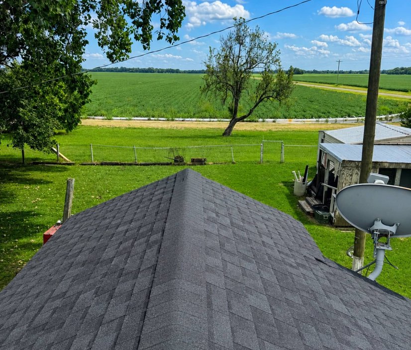 Ridge line of a newly installed charcoal shingle roof under a clear Mississippi sky