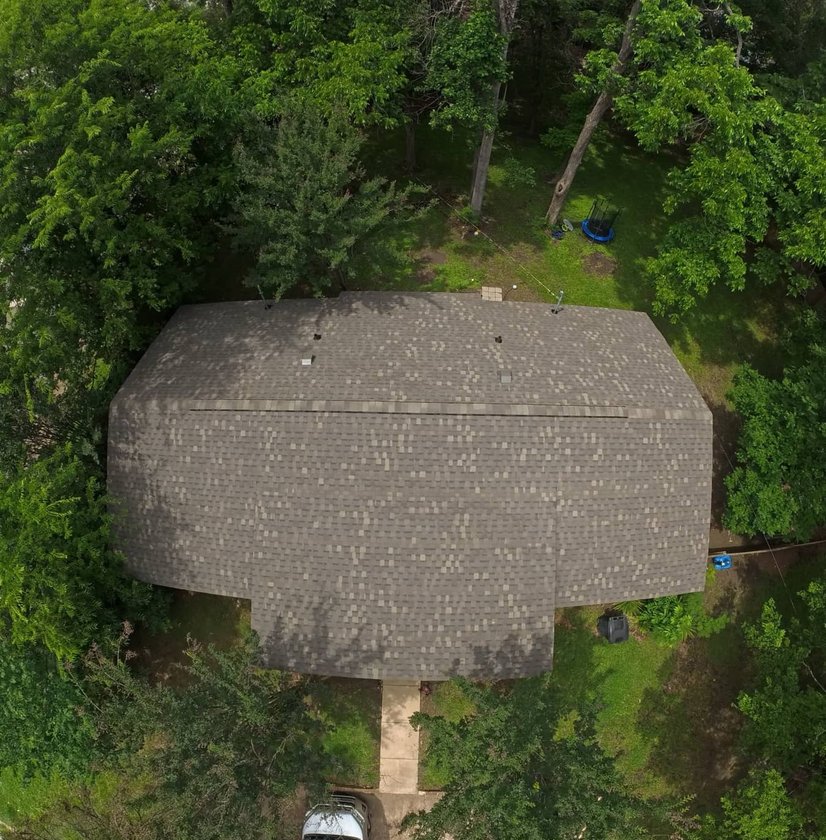 Aerial view of a new shingle roof on a wooded lot in Ridgeland, MS