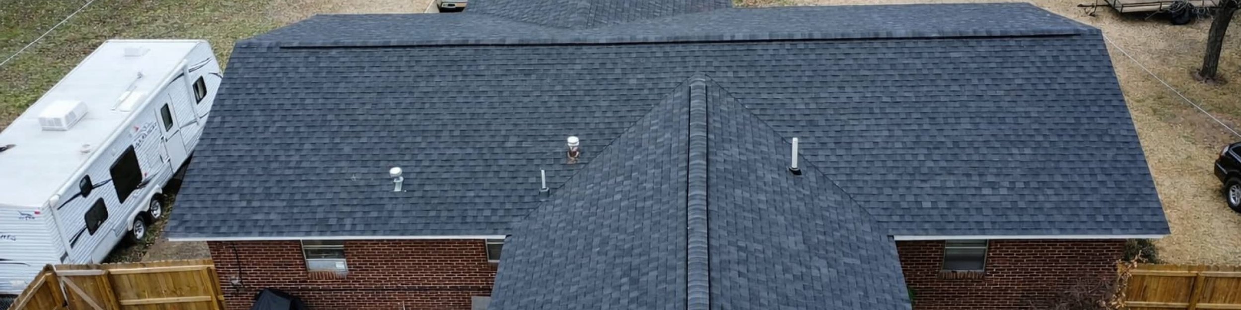 Aerial view of a new black shingle roof on a brick home with a fenced backyard