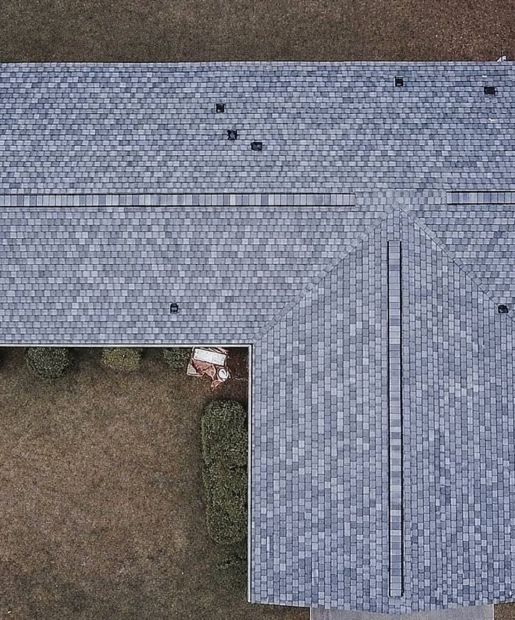 Overhead view of a light grey architectural shingle roof on an L-shaped home